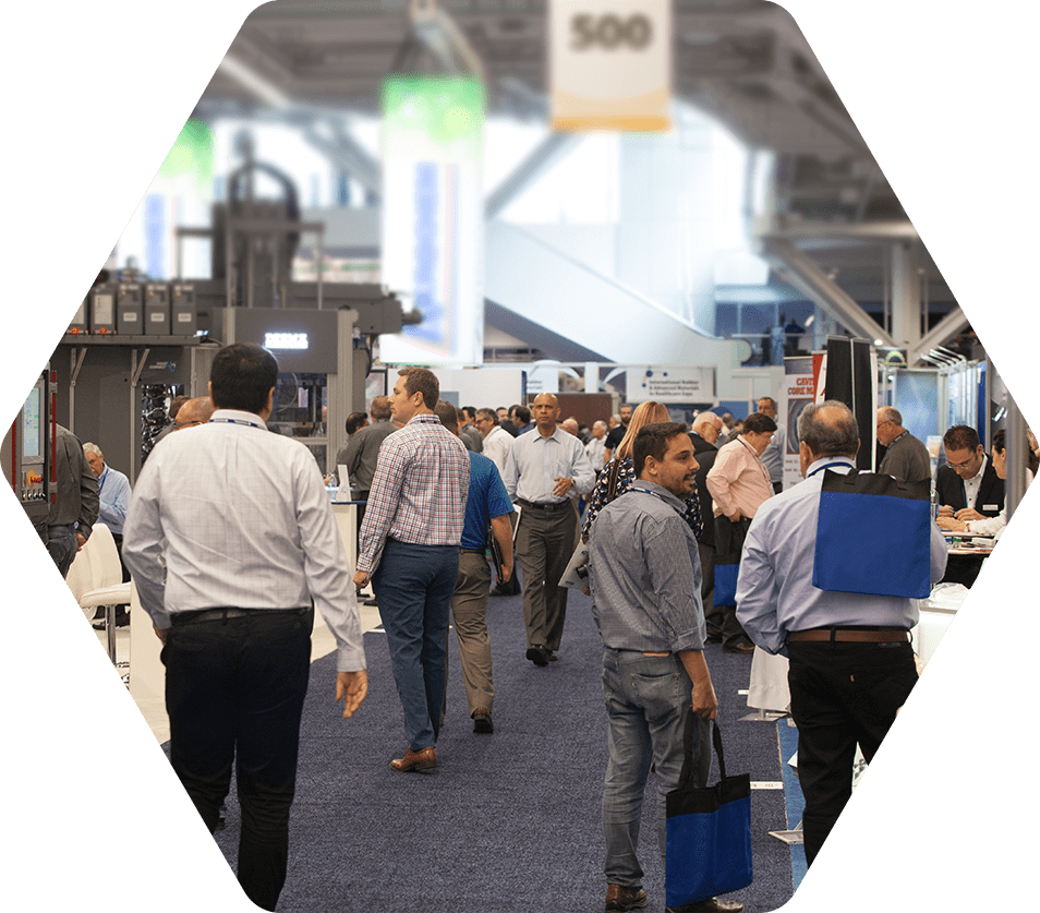 Attendees of an indoor conference walking through event booths and conversing with other attendees